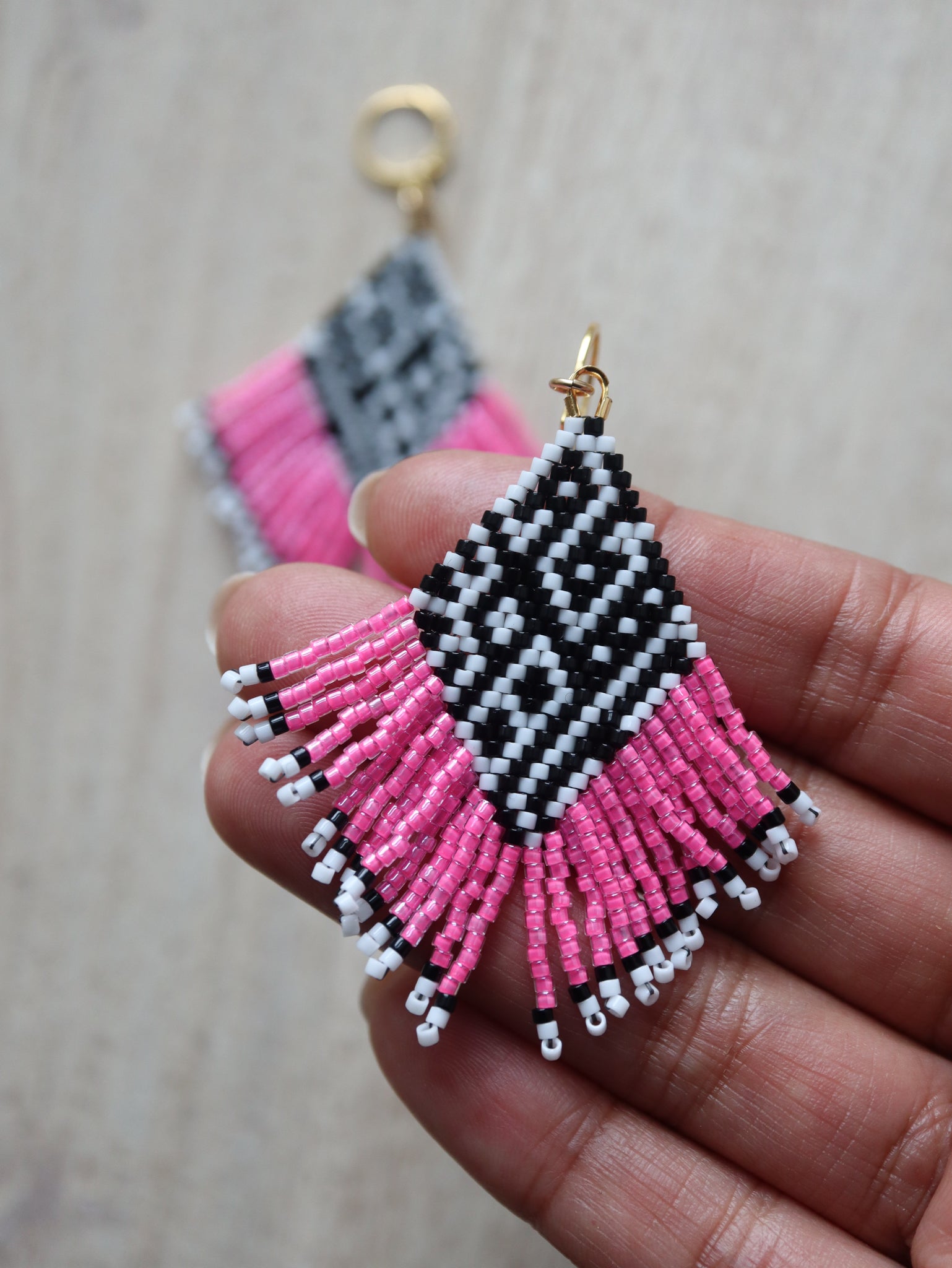 beaded black and white earring with hot pink fringe and tribal feel